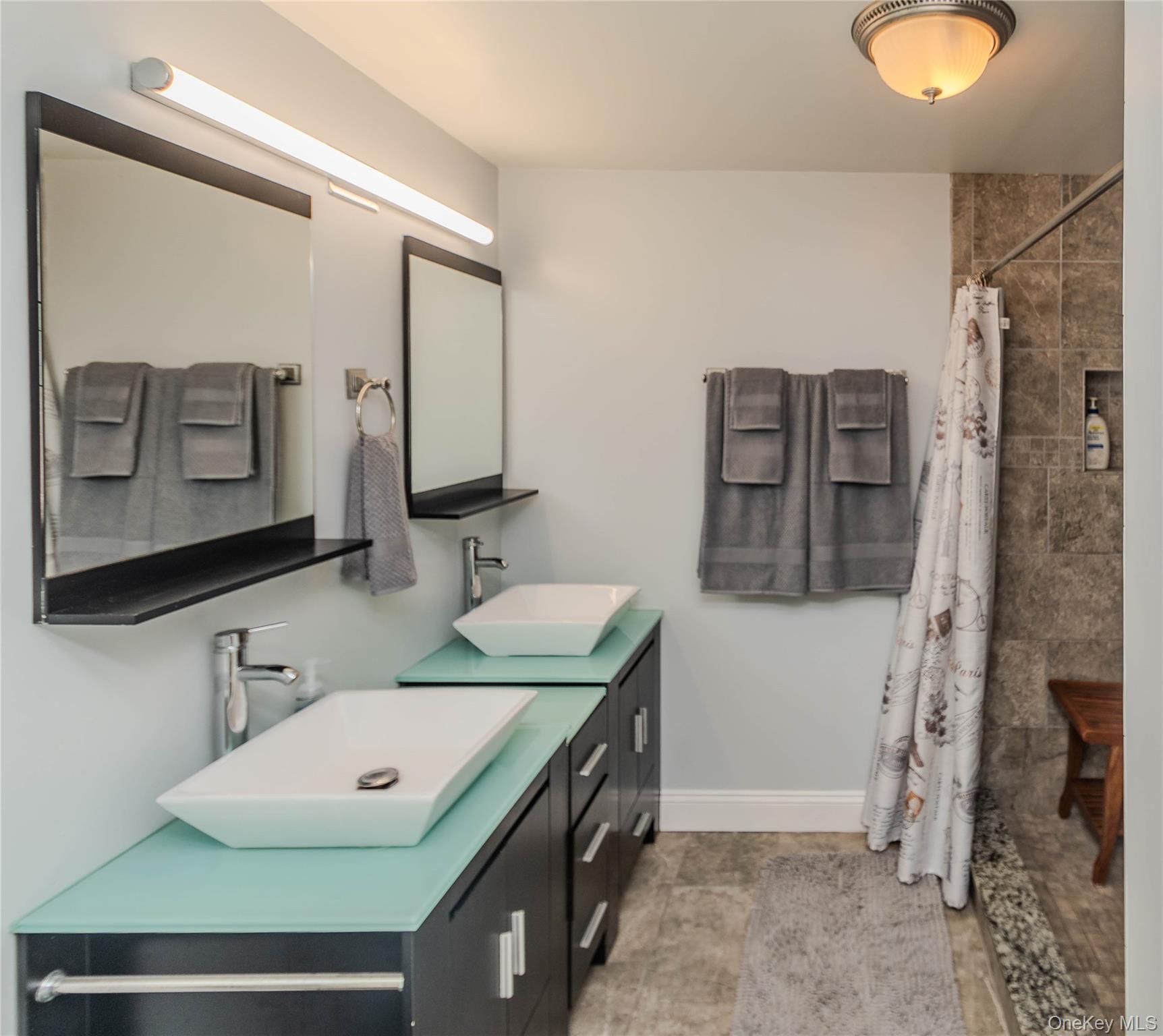 15 Van Dewark Road Middletown, NY 10941 - Photo 26 of 41 Dual vessel sinks with modern chrome faucets set on two separate vanities featuring light aqua glass countertops and dark cabinetry