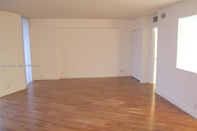 a view of empty room with wooden floor