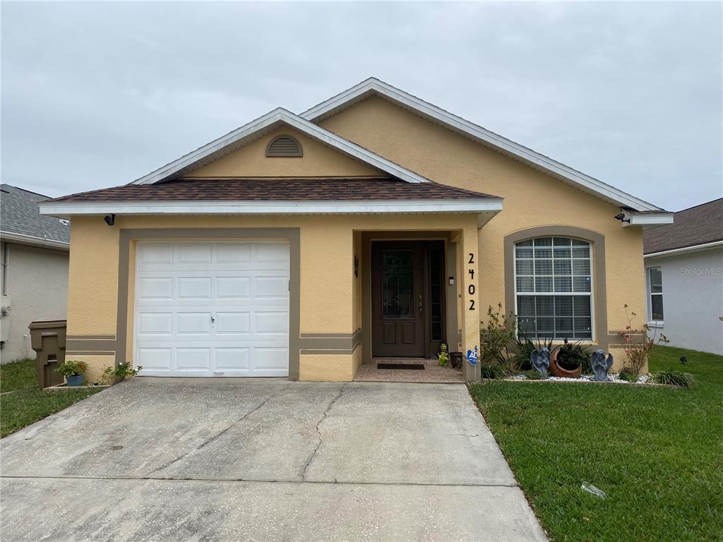2402 Ruddenstone Way Kissimmee, FL 34744 - Photo 1 of 1 a front view of a house with a yard and garage