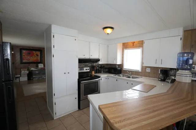 a kitchen with a refrigerator a stove a sink dishwasher with a dining table and chairs