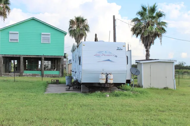 front view of a house with a yard and palm trees