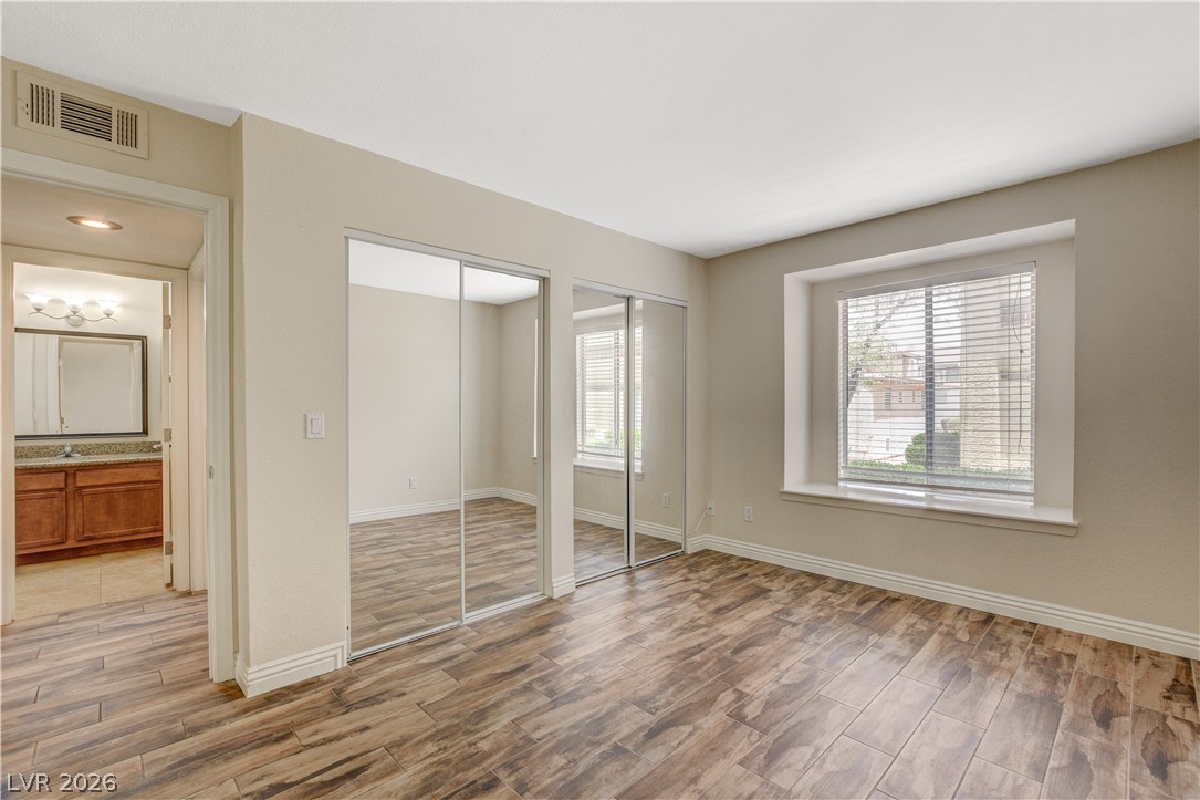 7200 West Pirates Cove Road, Unit 1026 Las Vegas, NV 89145 - Photo 23 of 35 This spacious bedroom offers ample natural light and direct access to a well-appointed bathroom.