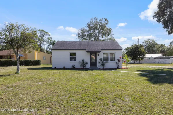 a view of a house with a backyard and a tree