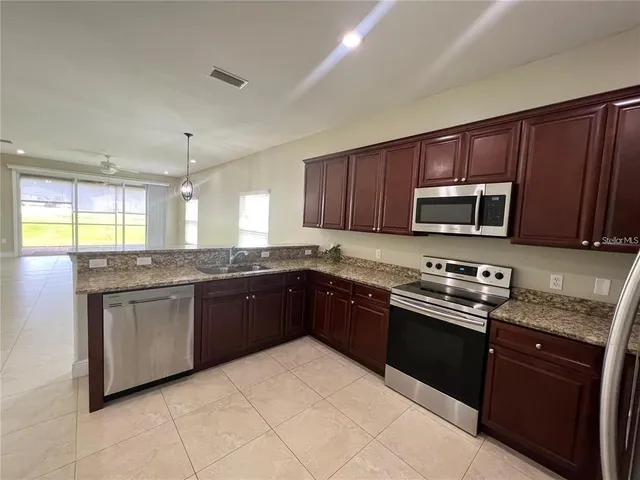 a large kitchen with granite countertop stainless steel appliances and wooden cabinets