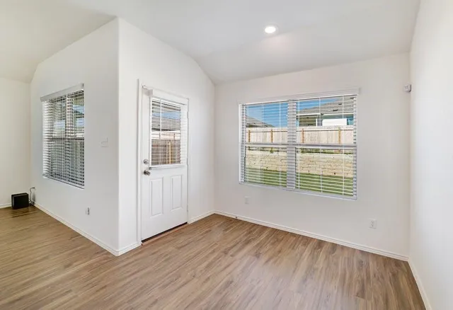 an empty room with wooden floor and windows