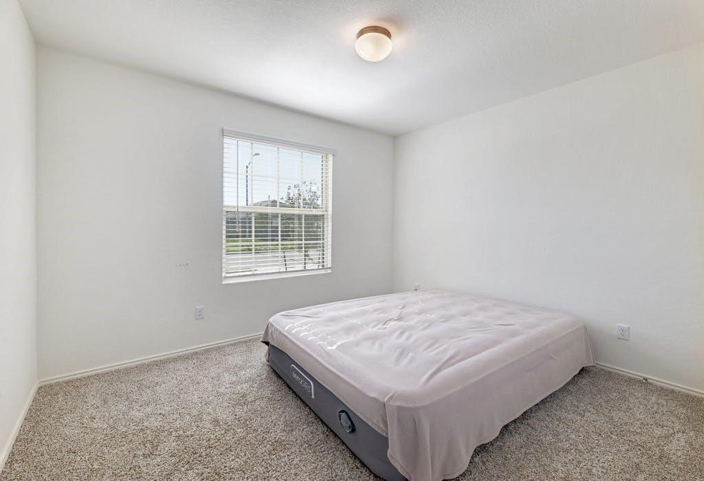 21416 Bird Wing Drive Pflugerville, TX 78660 - Photo 16 of 25 a bed sitting in a bedroom next to a window