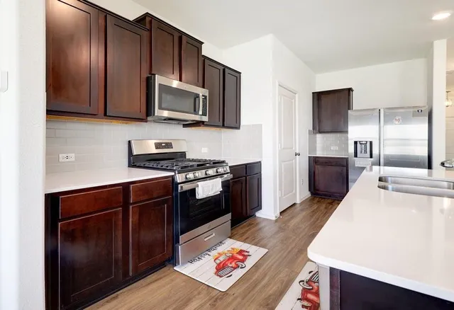 a kitchen with stainless steel appliances kitchen island granite countertop wooden floors and wooden cabinets