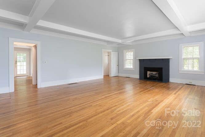 2853 Chimney Rock Road Hendersonville, NC 28792 - Photo 6 of 36 an empty room with wooden floor fireplace and windows