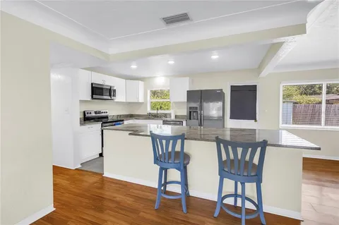 a kitchen with stainless steel appliances a dining table chairs microwave and sink