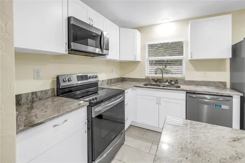 a kitchen with granite countertop a stove sink and microwave