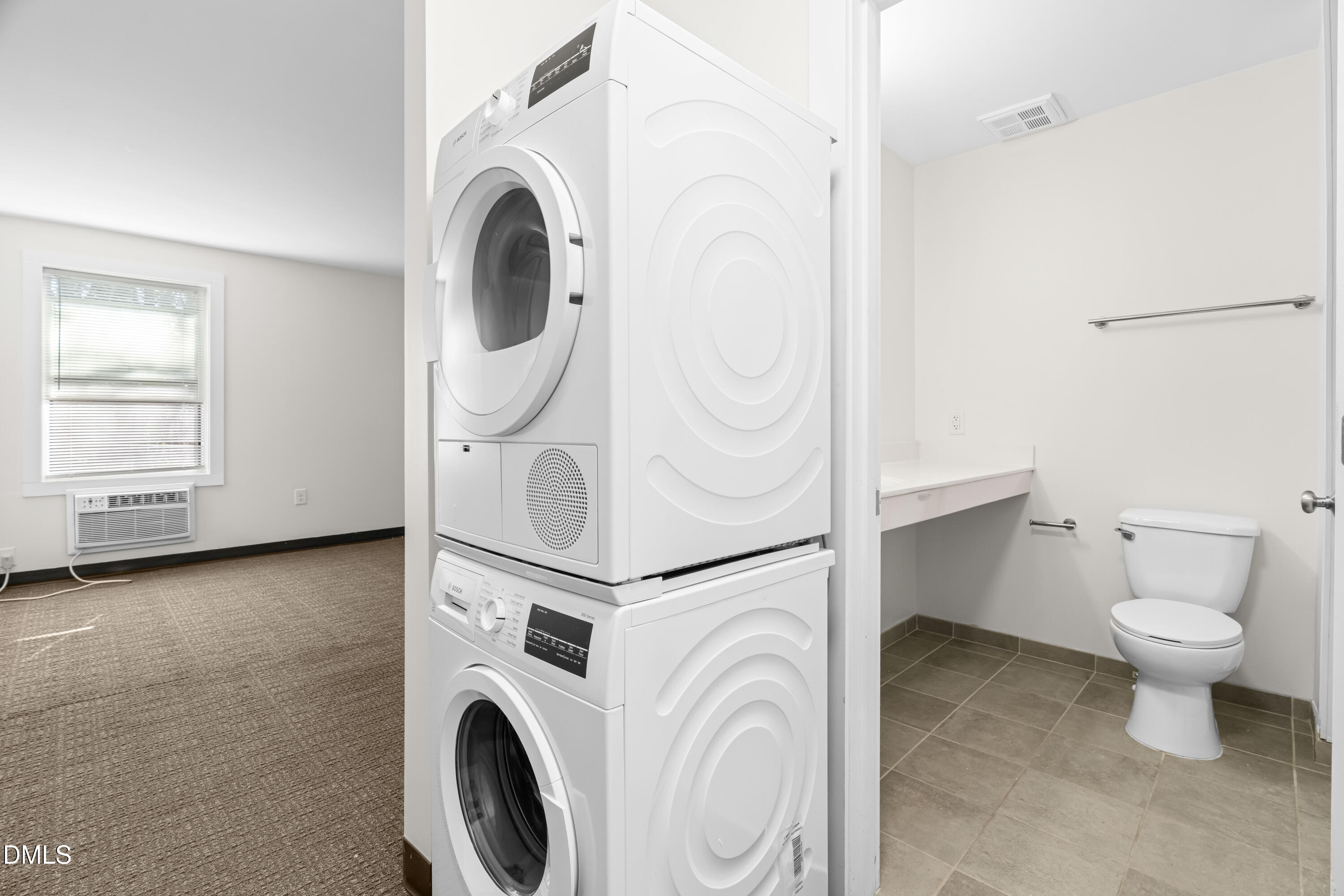 5104 Hollyridge Drive, Unit 303 Raleigh, NC 27612 - Photo 3 of 21 a view of a storage and utility room with washer and dryer