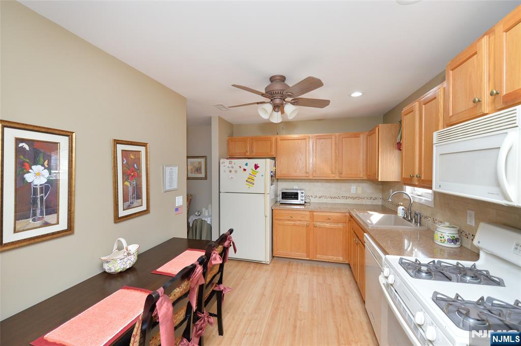 40 Chanda Court, Unit D040 Clifton, NJ 07012 - Photo 9 of 17 a kitchen with stainless steel appliances granite countertop a stove top oven a sink a dining table and chairs with wooden floor