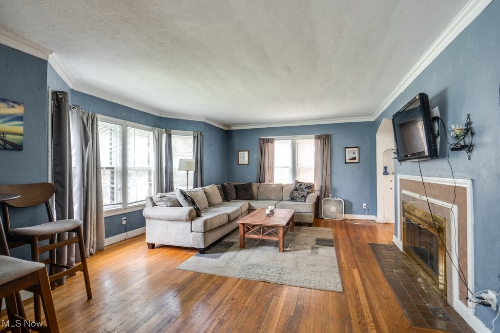 3709 Strandhill Road Shaker Heights, OH 44122 - Photo 6 of 25 Living room with a tiled fireplace, a textured ceiling, ornamental molding, and hardwood / wood-style flooring