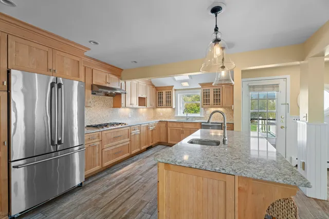 a kitchen with stainless steel appliances granite countertop a refrigerator a sink dishwasher a oven with white cabinets and wooden floor