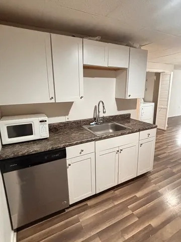 a kitchen with granite countertop white cabinets and a sink
