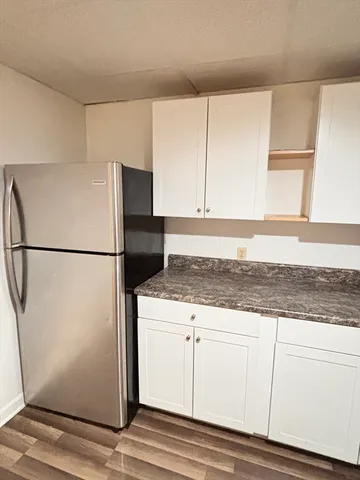 a kitchen with granite countertop white cabinets and refrigerator