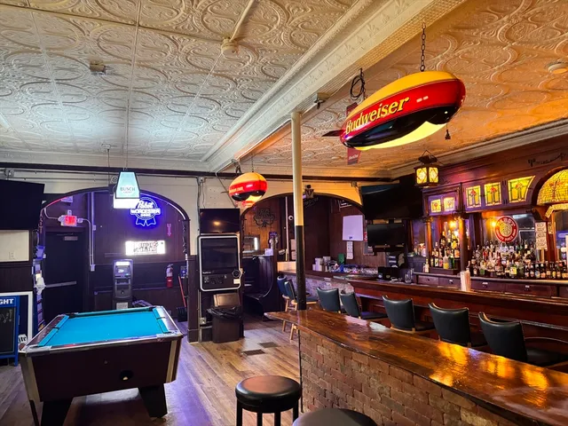 a kitchen area with stainless steel appliances kitchen island granite countertop a stove a dining table and chairs with the view of living room