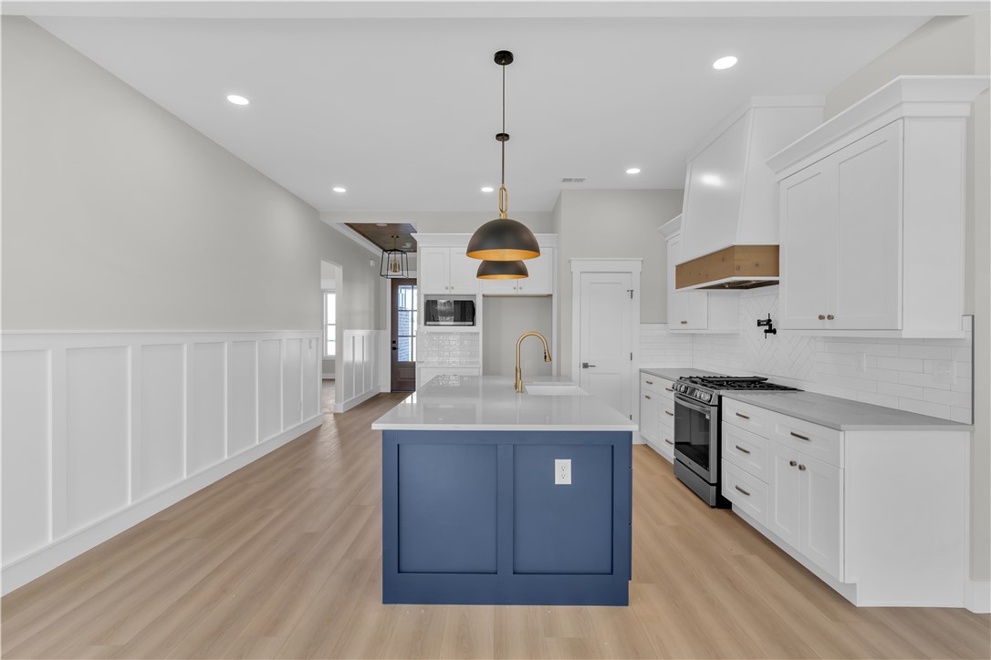 516 Lakeside Drive Anderson, SC 29621 - Photo 16 of 32 A contemporary kitchen features a blue island with a built-in sink and sleek pendant lighting.
