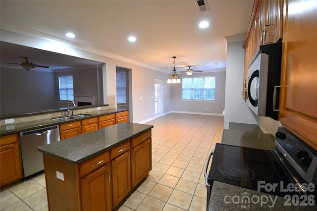 a kitchen with kitchen island granite countertop a stove a sink and a refrigerator