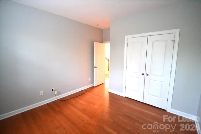 an empty room with wooden floor and closet area
