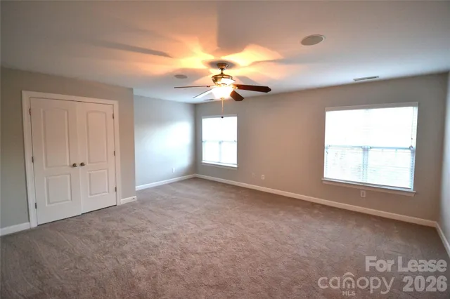 an empty room with windows and fan