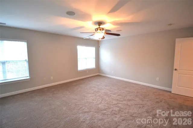 an empty room with windows and chandelier fan