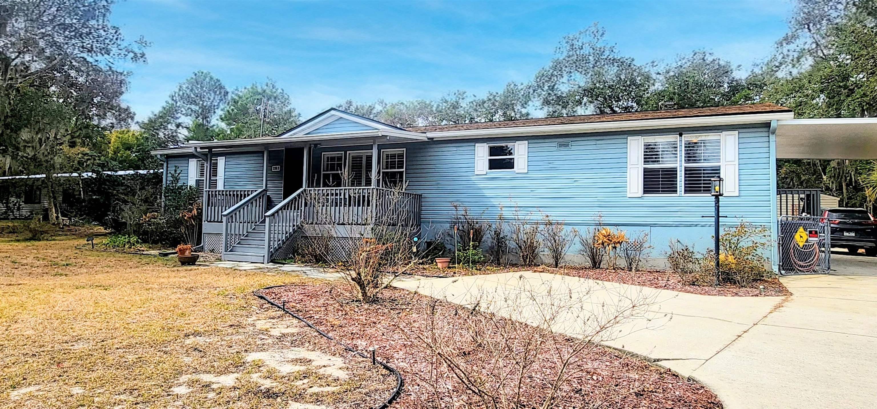 Manufactured / mobile home with concrete driveway and an attached carport
