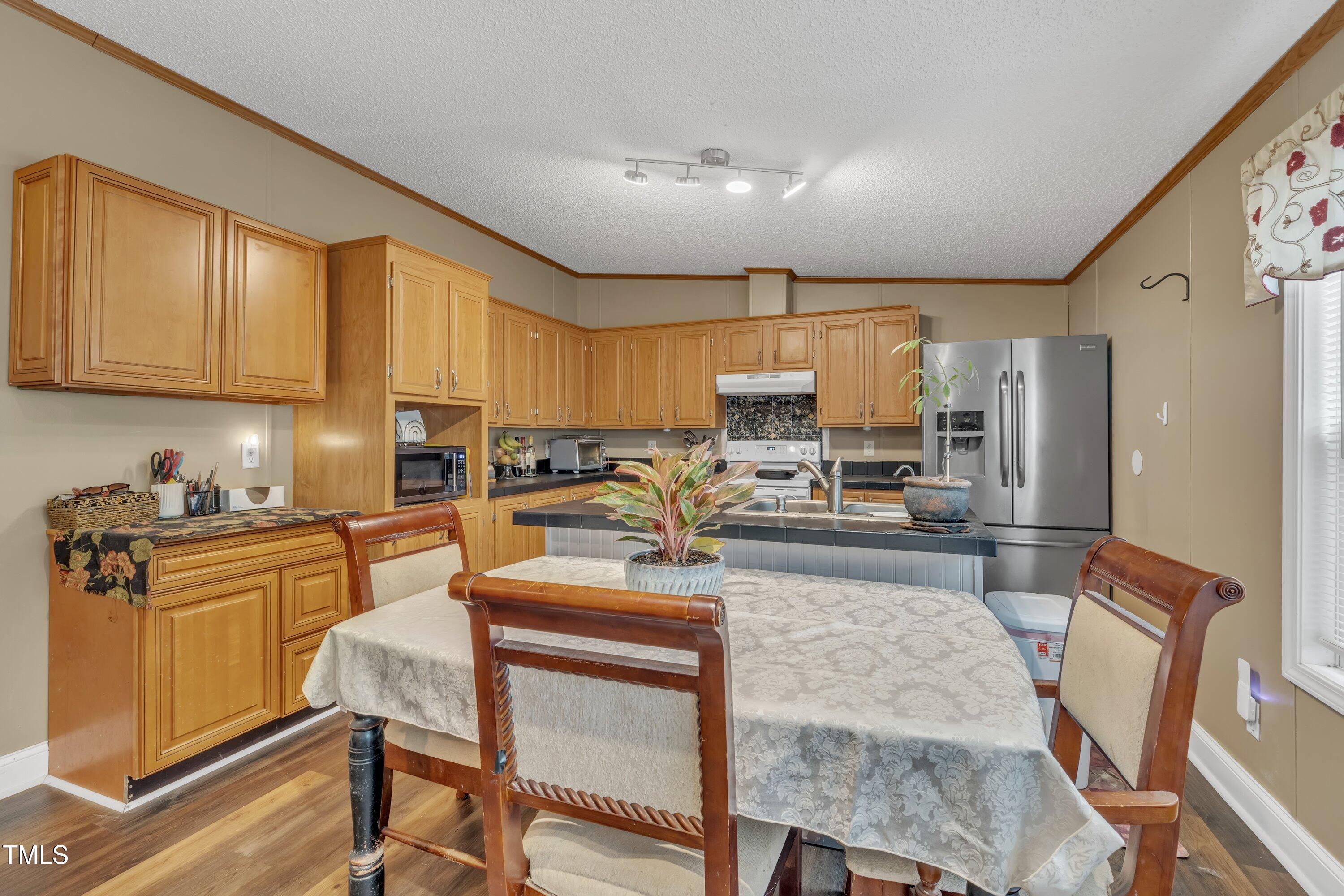 8904 Kennebec Road Willow Spring, NC 27592 - Photo 23 of 42 a kitchen with granite countertop a stove a sink a refrigerator cabinets and dining table