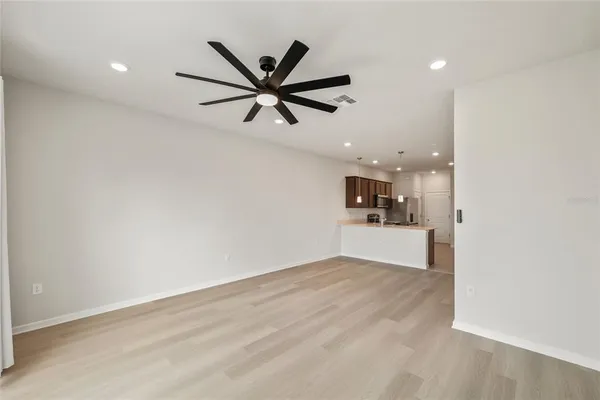 a view of a livingroom with a chandelier fan and wooden floor