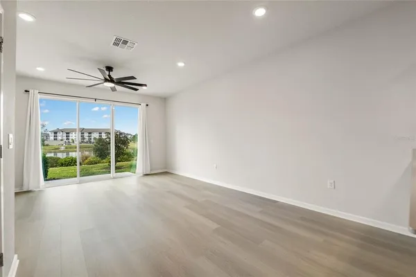 a view of an empty room with a window and wooden floor