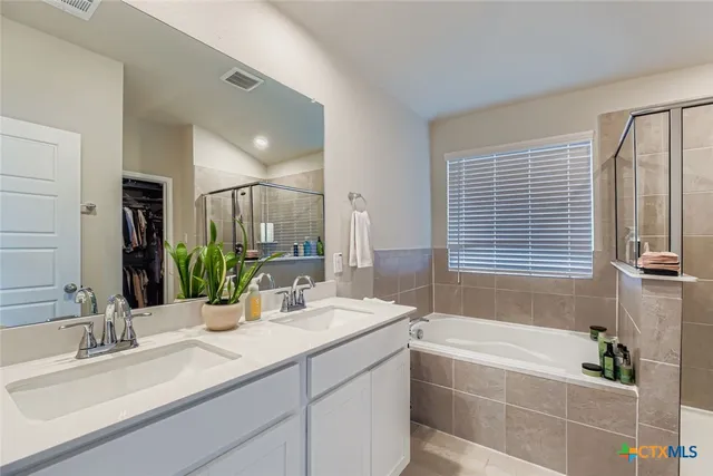 a bathroom with a double vanity sink large mirror and a bathtub