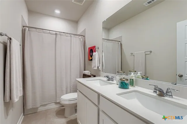 a bathroom with a double vanity sink mirror and toilet