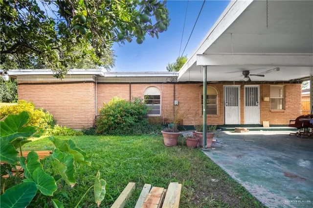 a backyard of a house with table and chairs under an umbrella