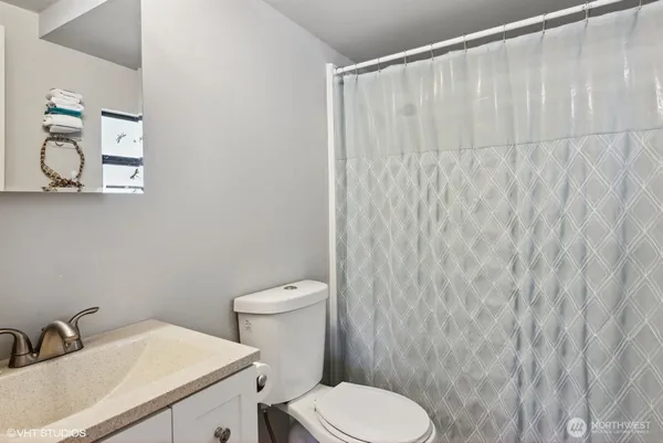 a bathroom with a sink a toilet and shower curtain