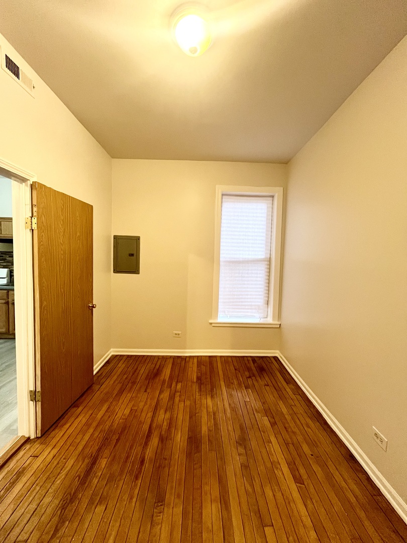 3227 South Carpenter Street, Unit 1M Chicago, IL 60608 - Photo 8 of 14 a view of an empty room with wooden floor and a window