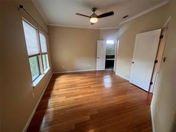 a view of an empty room with wooden floor and a window