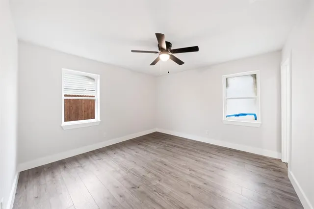 a view of empty room with wooden floor and fan