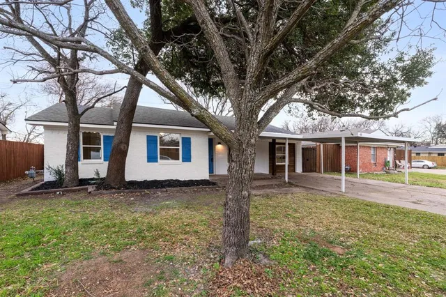 a view of a yard in front of a house with large tree