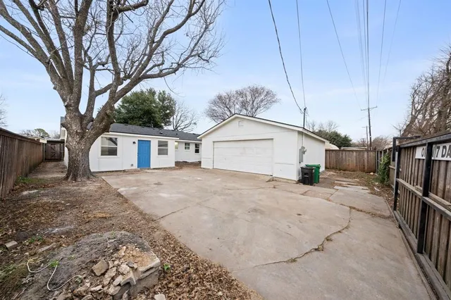 a front view of a house with a dirt yard and a large tree