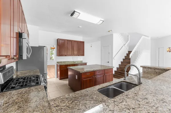 a kitchen with granite countertop a sink stove and refrigerator