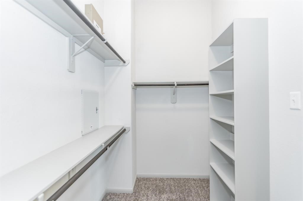 6447 Escondido Drive Rosharon, TX 77583 - Photo 12 of 16 Organize in style with this spacious walk-in closet, complete with built-in shelves and multiple hanging options. Designed with functionality and storage in mind, this closet provides ample space to keep everything in order. A perfect complement to the luxurious primary suite.