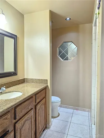 a bathroom with a granite countertop sink a toilet mirror and vanity
