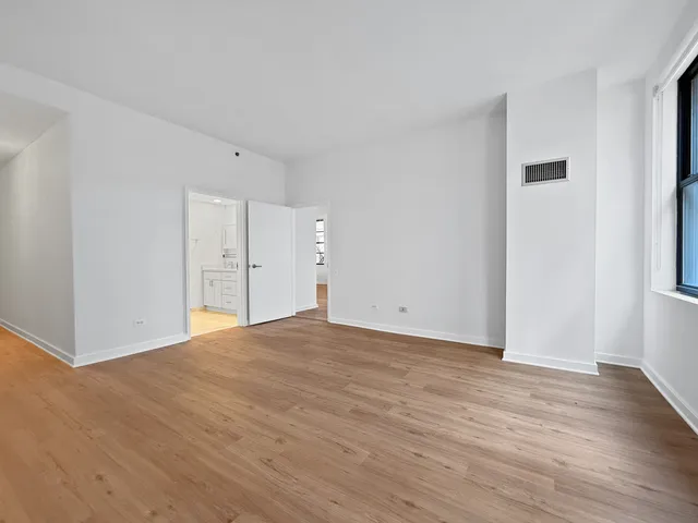 a view of an empty room with wooden floor and windows