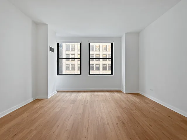 a view of an empty room with wooden floor and windows