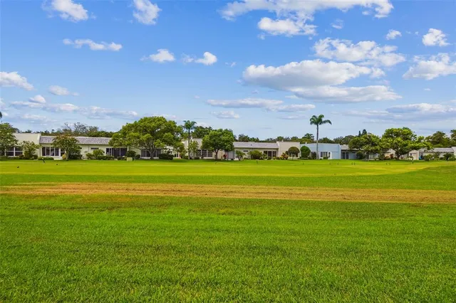 a sign of golf club on a wall under a tree