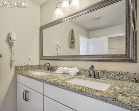 6564 Watusi Road Peyton, CO 80831 - Photo 10 of 12 a bathroom with a granite countertop sink and a mirror