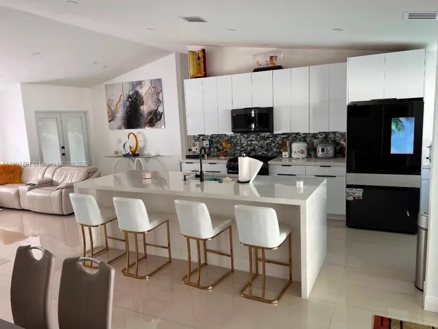 a kitchen with stainless steel appliances kitchen island granite countertop a sink and a refrigerator
