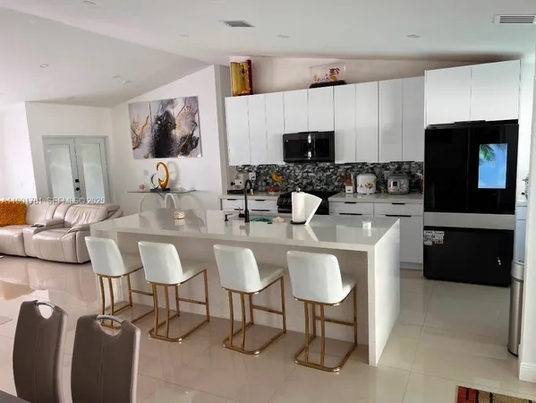 a kitchen with stainless steel appliances kitchen island granite countertop a sink and a refrigerator