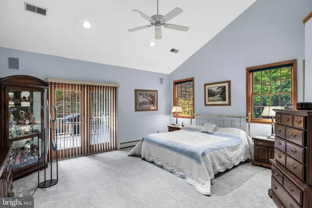 a bedroom with a bed a dresser and a large window