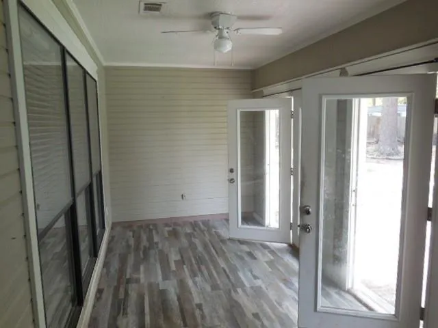 a view of a hallway with wooden floor and a bathroom